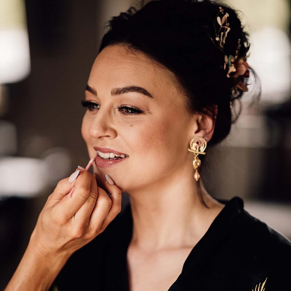 Bride in a black satin robe gets her makeup done for the wedding day 