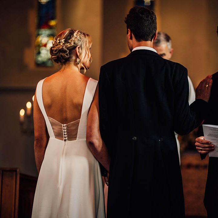 The bride and groom at their church wedding ceremony with a groomsman performing a wedding reading