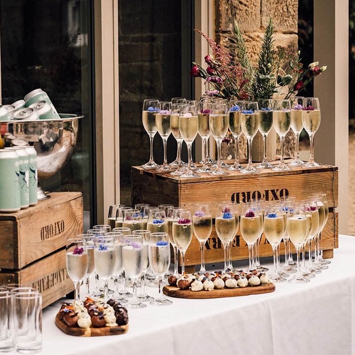 Wedding drinks and favours station with glasses of champagne with purple edible flowers for decoration 