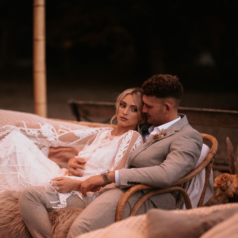 Bride and groom sitting on boho rattan wedding seating