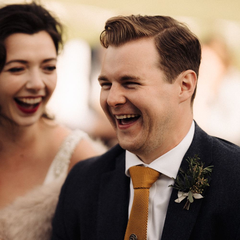 Bride & groom laugh during wedding reception speeches