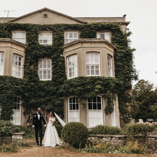 Bride and groom portrait outside their wedding venue, Northbrook Park, with the bride in a Oleg Cassini wedding dress and the grooms wearing a velvet tuxedo 