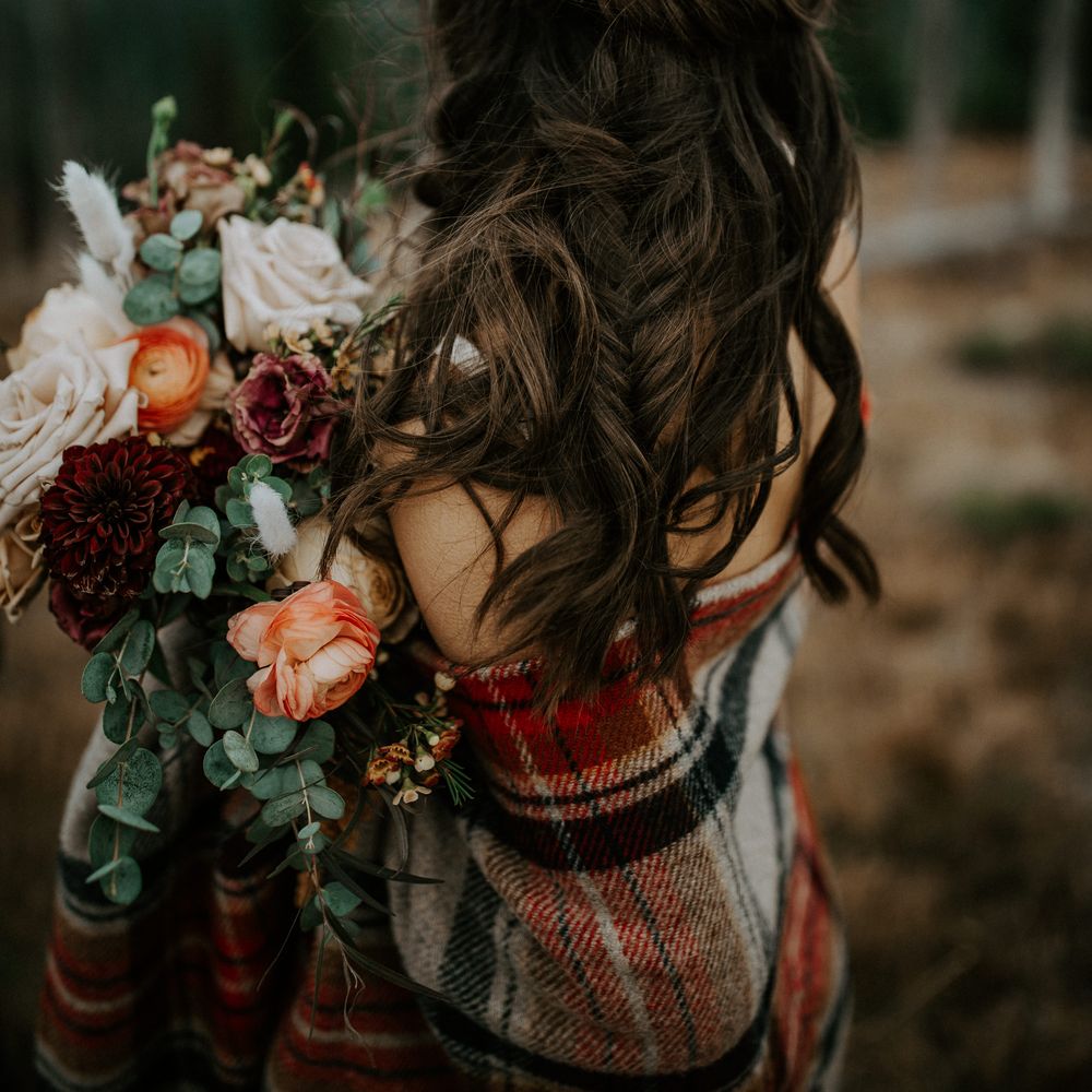 Bride wears her dark hair in loose curls with fishtail plait running through