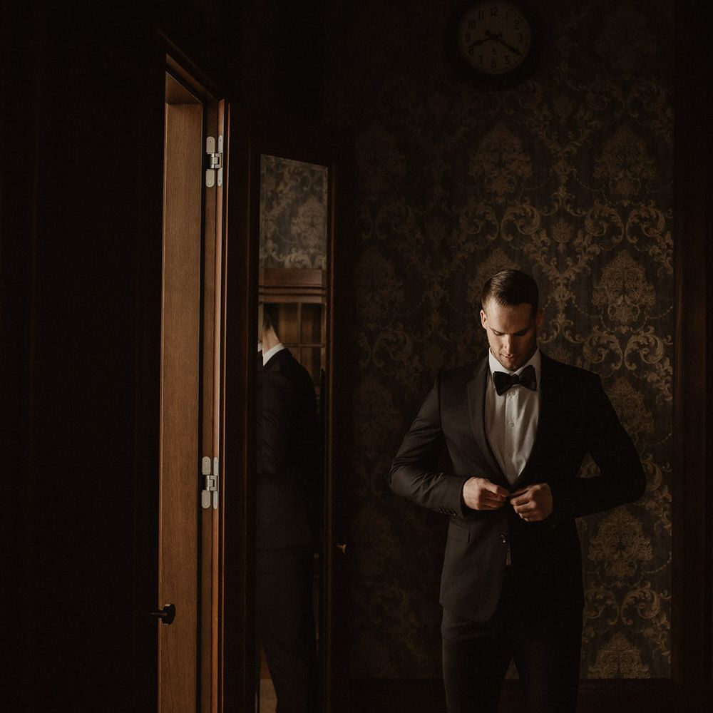 Groom fastening his black wedding suit blazer
