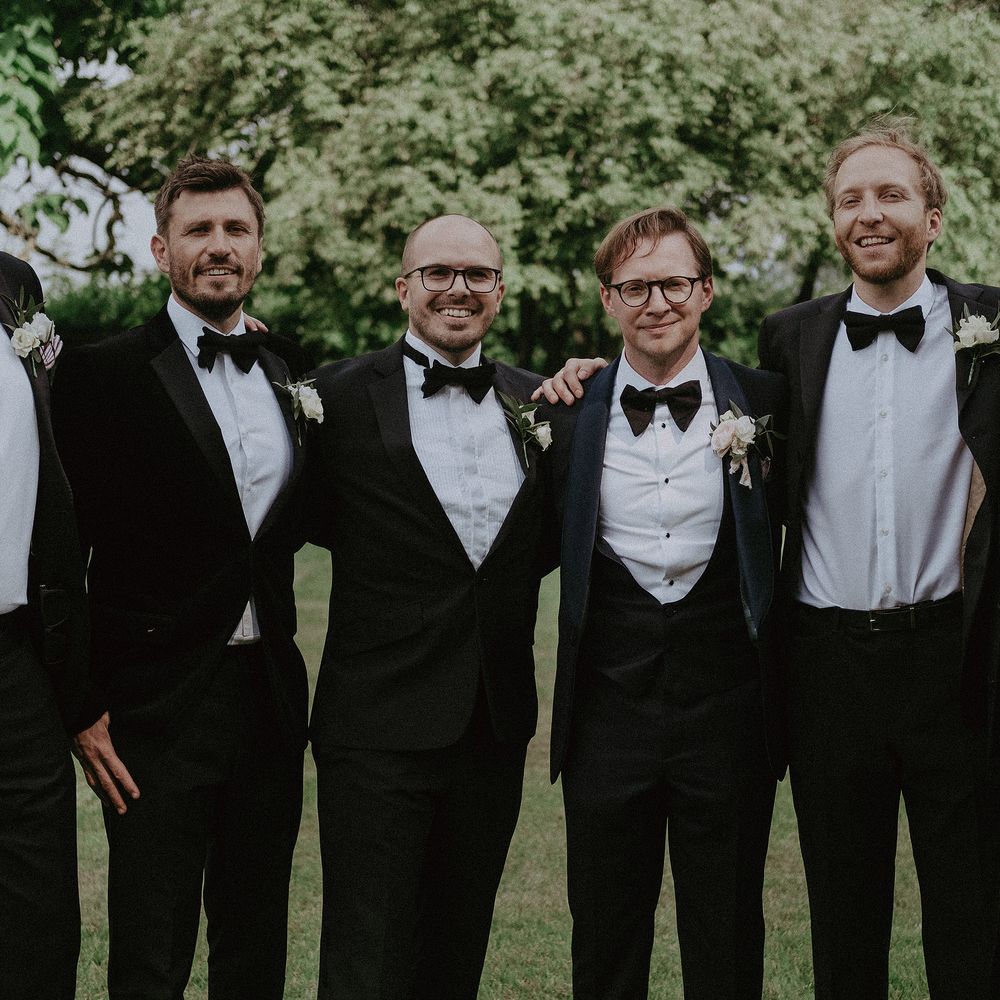 Groom stands with his groomsmen in black tie for classic wedding at Elmore Court