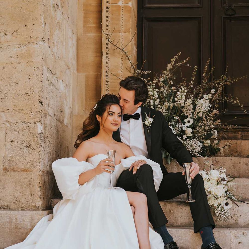 Groom in a tuxedo kissing his brides head on the steps at Bodleian Library 