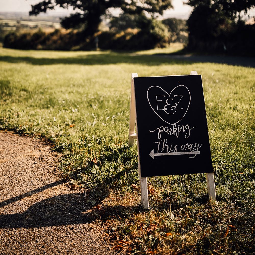 Chalkboard wedding welcome sign in field for Cornwall garden wedding with Halfpenny London Mayfair dress
