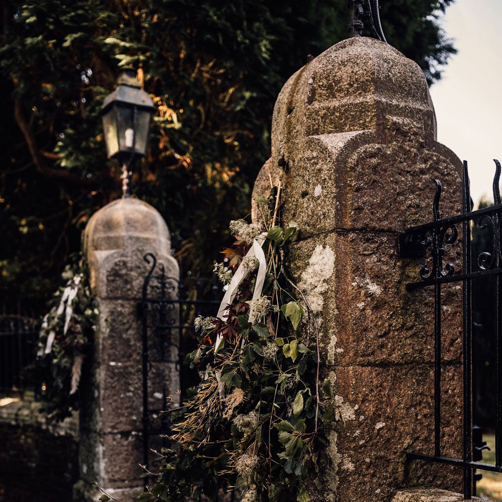 Stone driveway entrance with florals and ribbon hanging for Cornwall wedding
