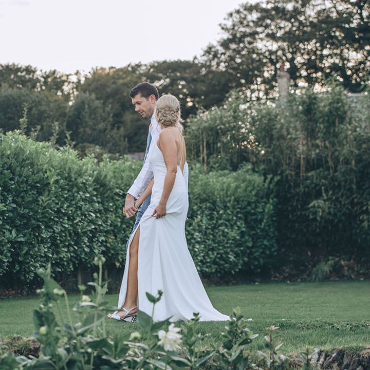 Bride and groom walk through the gardens of Trevenna Barns