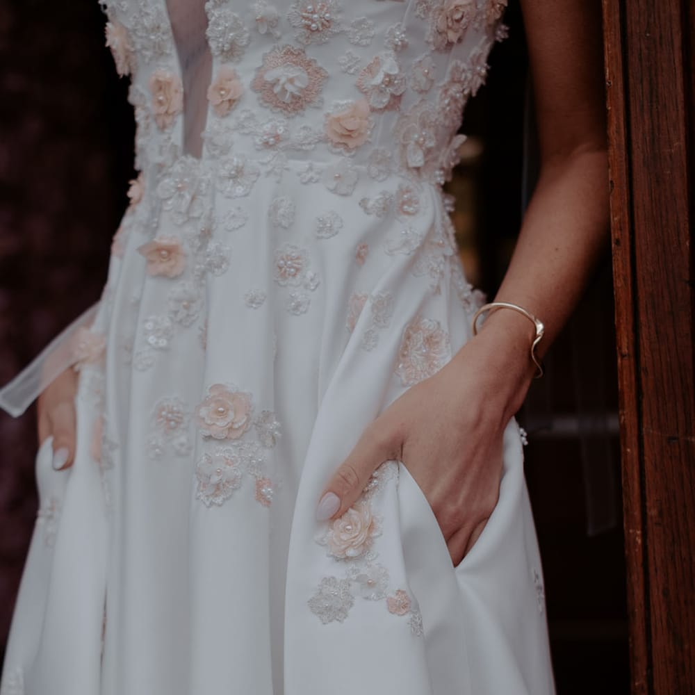 Satin wedding dress with peach and white appliqué flower details and pockets 