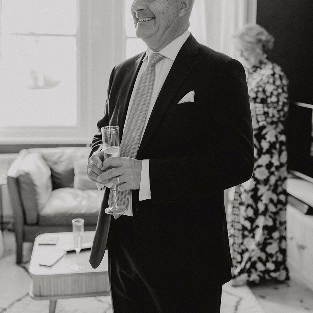 Father of Bride looks at his daughter on her wedding day whilst holding a glass of champagne