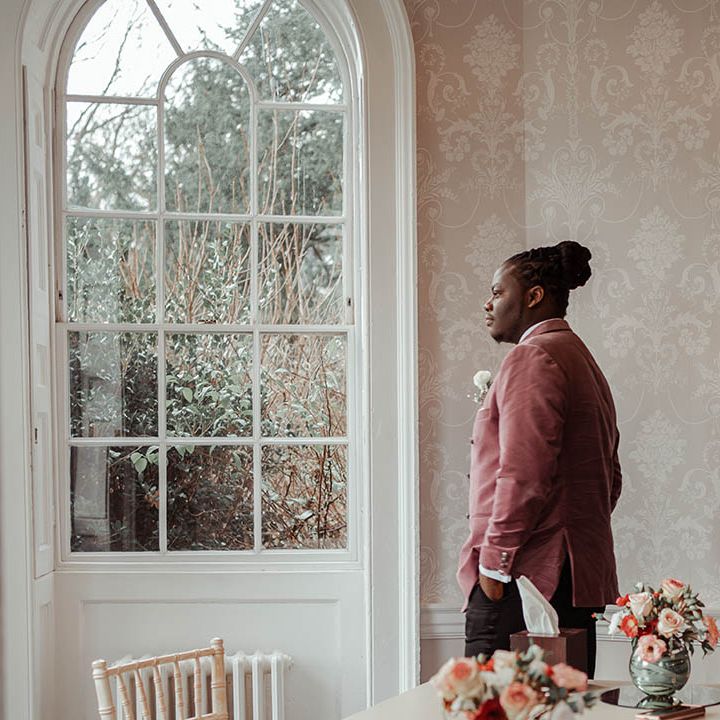 Groom looks out the window on his wedding day