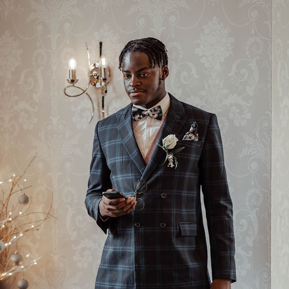 Groomsmen wears tartan suit complete with floral buttonhole 