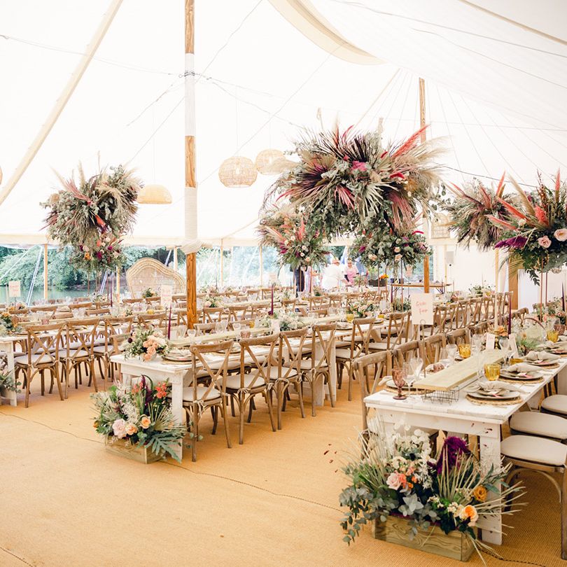 Marquee wedding with gorgeous flower decor hanging above the long wooden tables