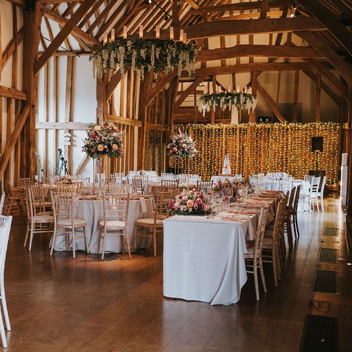 Exposed beam country house wedding venue with pink and copper tablescape with hanging flowers and centrepieces