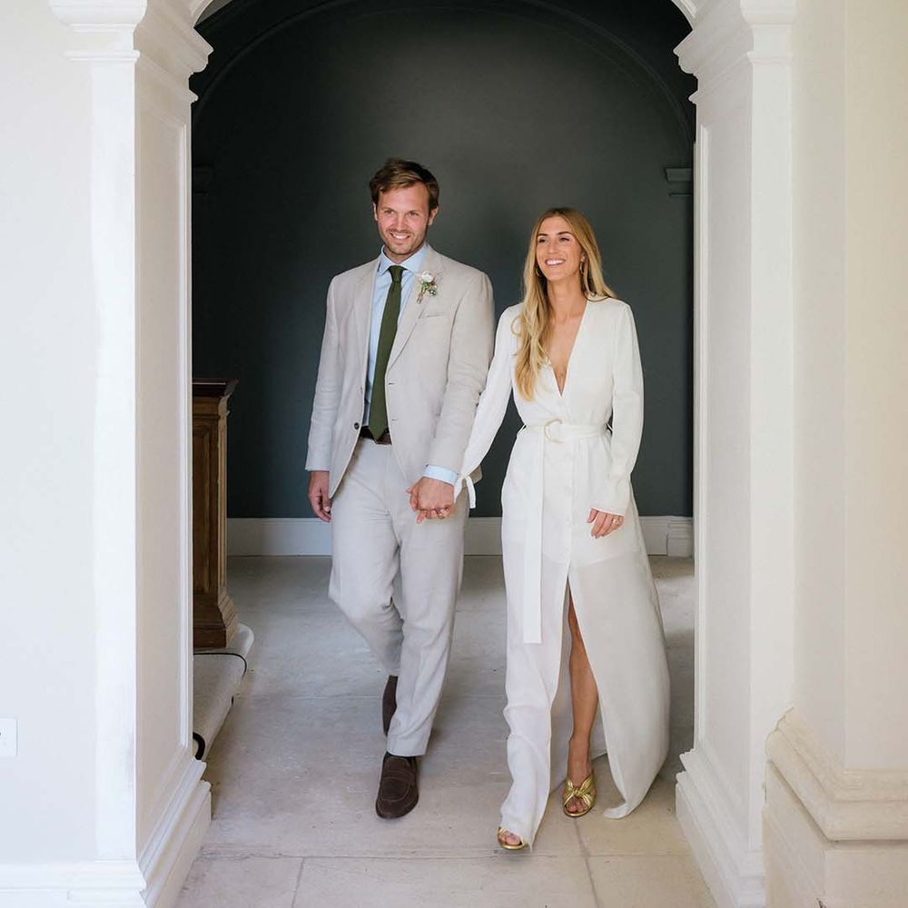 Bride in Bon Bride plunging neckline, long sleeved, front slit wedding dress with belt and Saint Laurent gold mules with groom in cream suit and green tie 