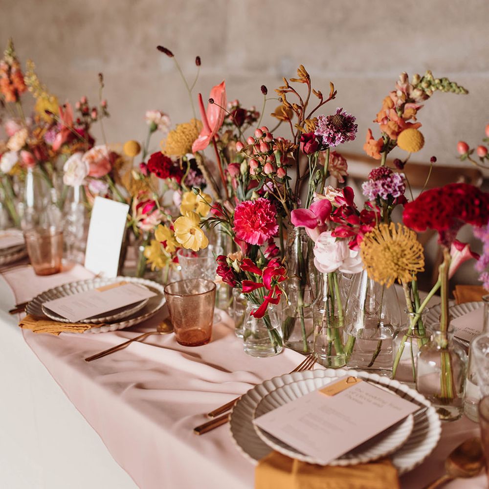 Place settings and table centrepiece flowers and decor with yellow and pink billy buttons, anthuriums and carnations