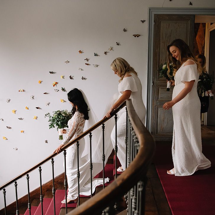 Bridesmaids in white sparkly front slit dresses follows the bride down the stairs to travel to the wedding ceremony 