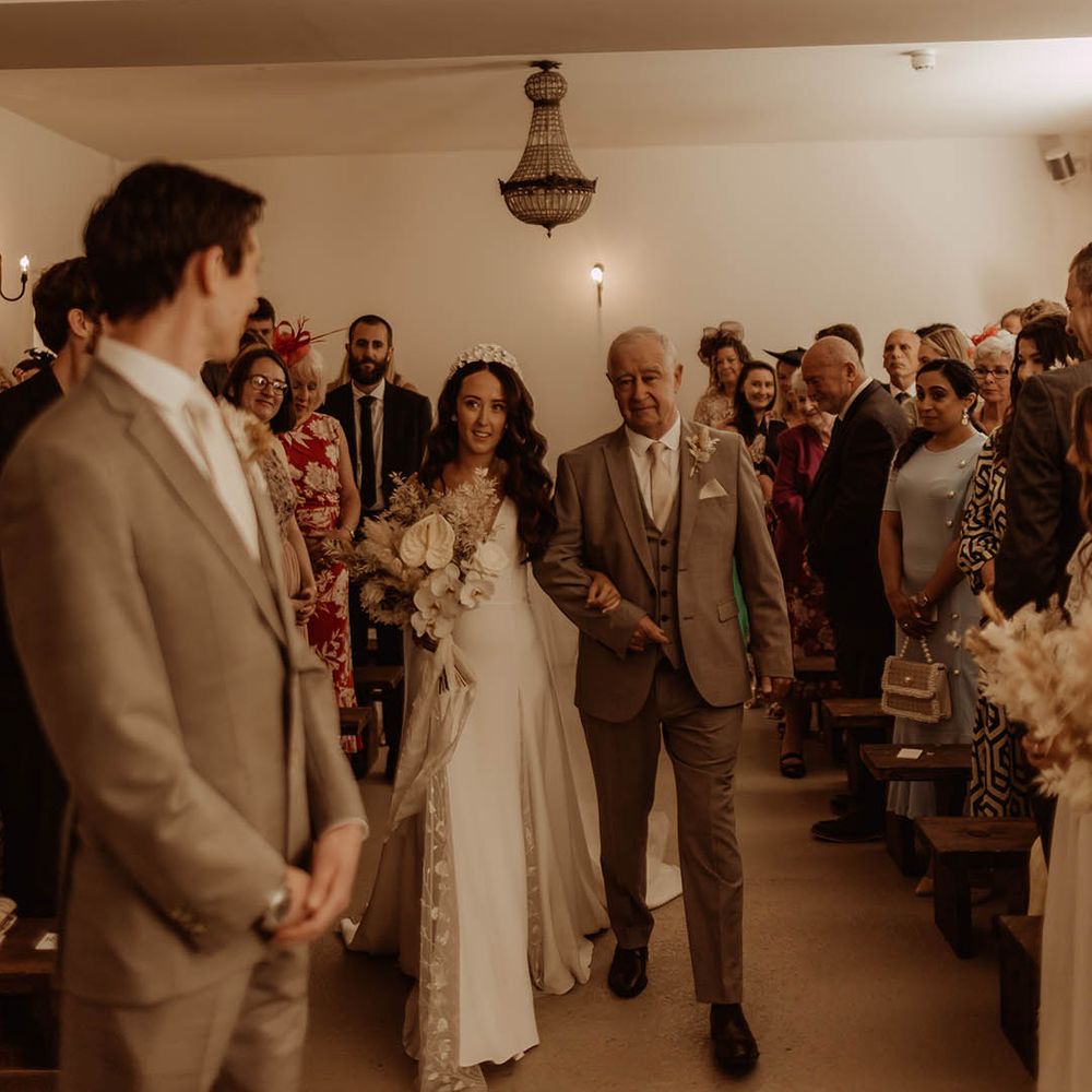 Father of the bride in neutral three piece suit walks the bride down the aisle for her boho luxe wedding at Aswarby Rectory 