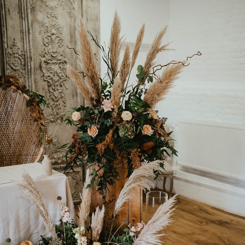 Pink, white and orange wedding flowers with pampas grass and white pillar candles in hurricane vases 