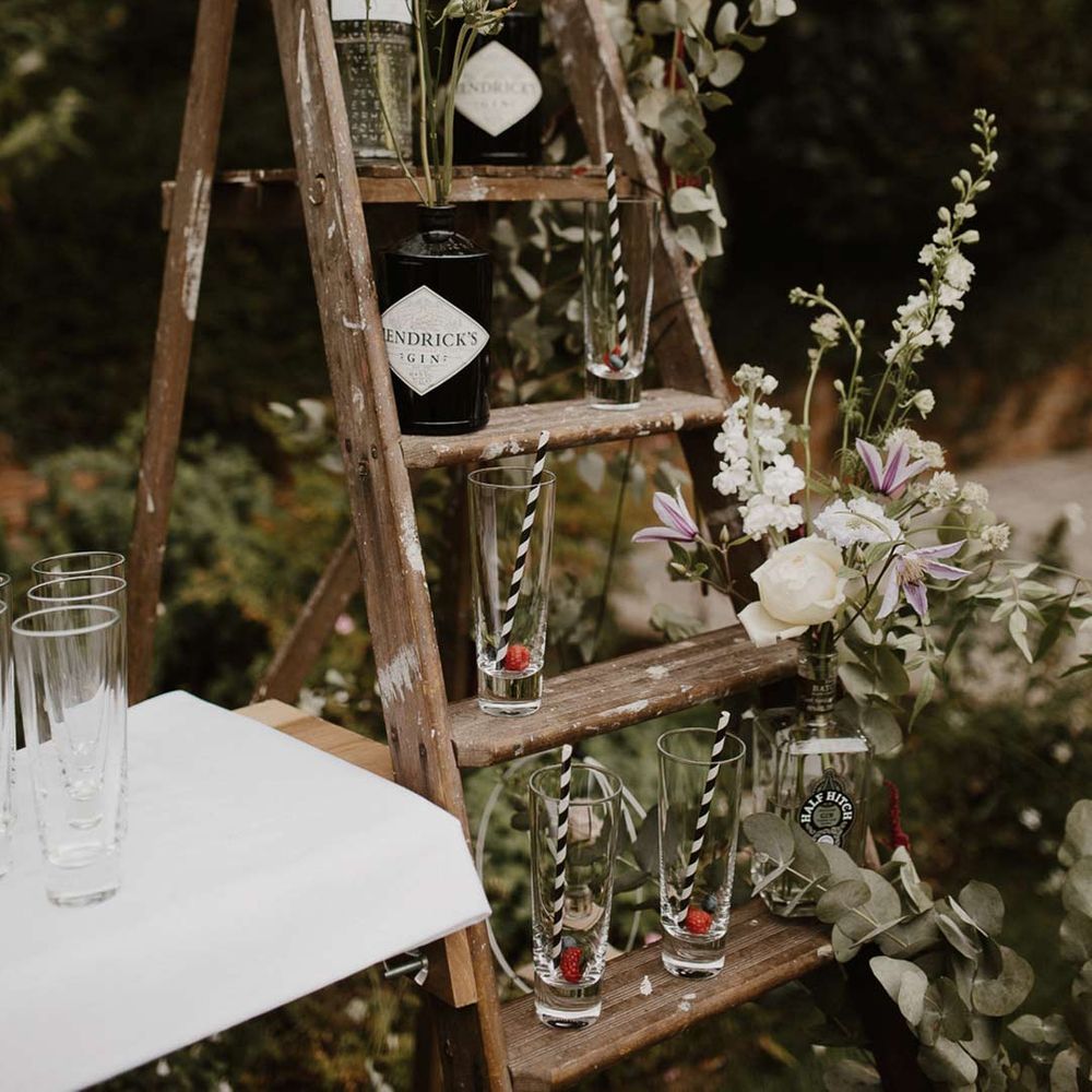 DIY wedding gin bar on an old ladder with florals and fauna draped off the sides