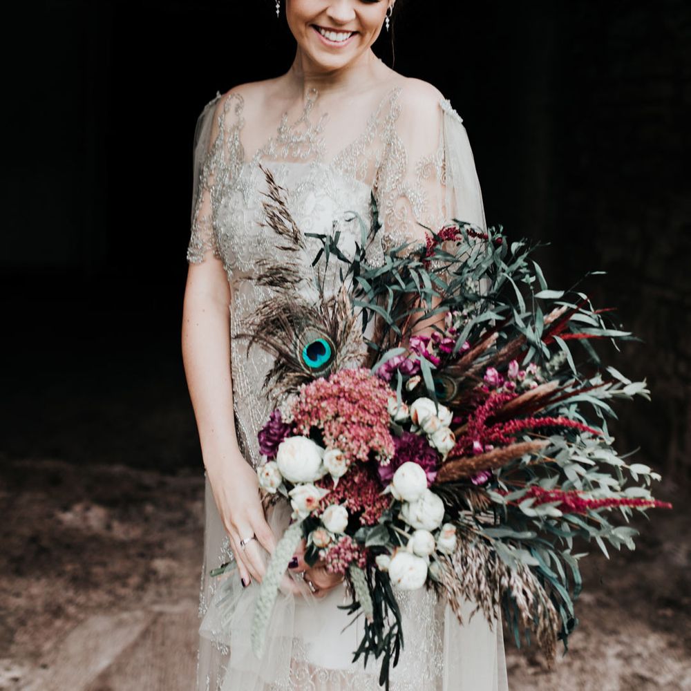 Homemade sage tinted quarter length sleeve wedding dress with homemade bouquet and peacock feathers