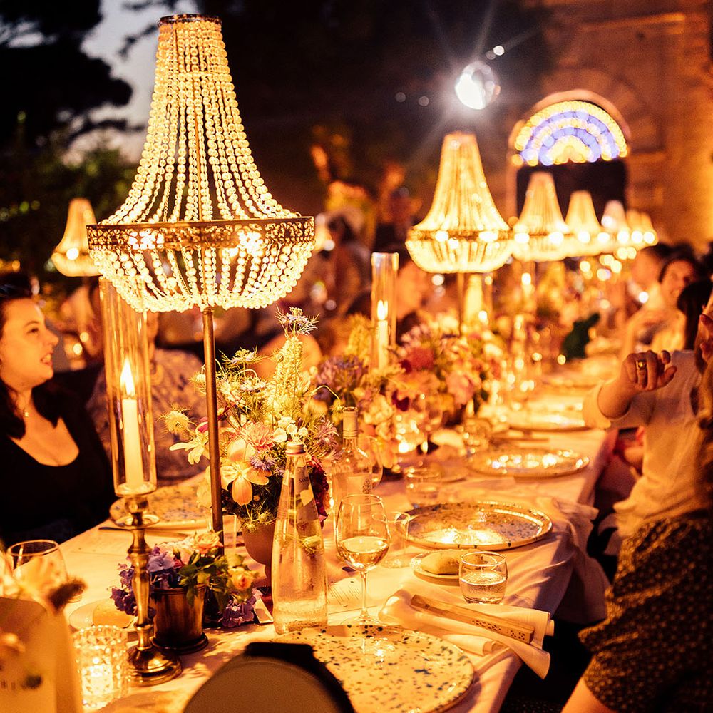 Lit up chandelier installations over the banquet tables at the wedding reception 