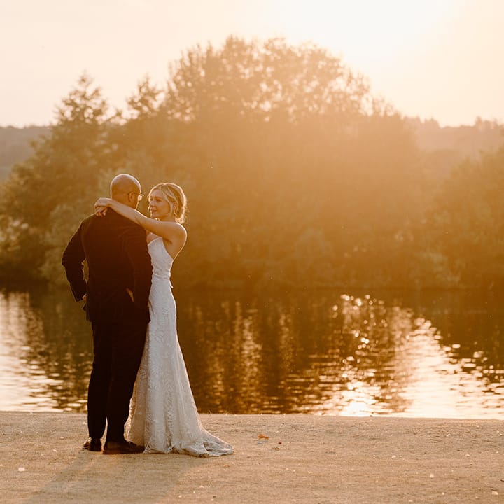 Bride & groom embrace outdoors by the River Thames during golden hour portraits 