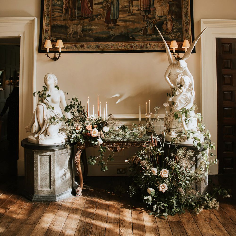Large hanging rug, white statues and neutral toned foliage with light candles decor at Elmore Court