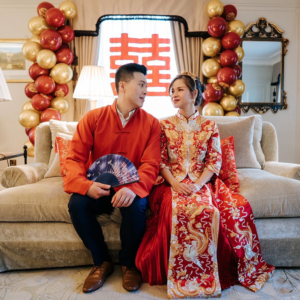 Groom holds colourful fan as he sits beside his bride on their wedding day