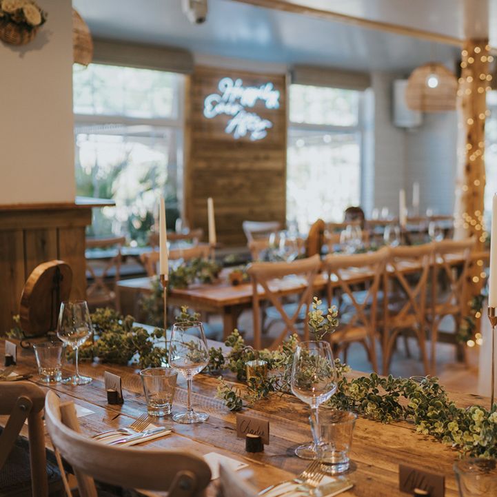 Rustic wooden banquet tables with green foliage table runner 