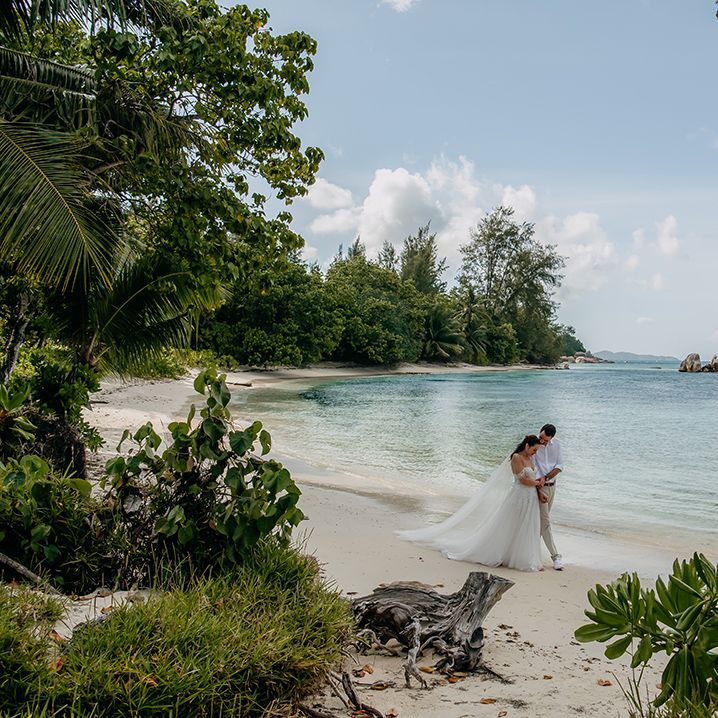 Bride and groom embracing and walking along the beach at Seychelles elopement