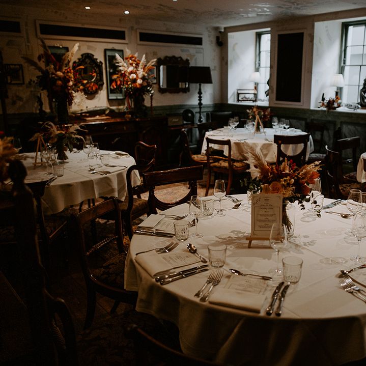 Circular wedding table at The Zetter Townhouse with white table cloth, large autumnal floral arrangement in clear vase 