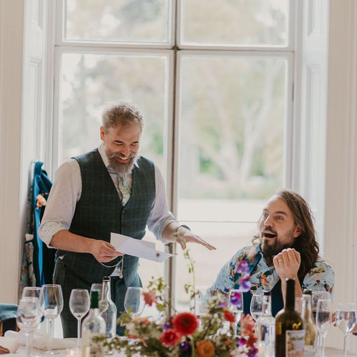 Groom in tartan waistcoat and white shirt reads speech during intimate reception 