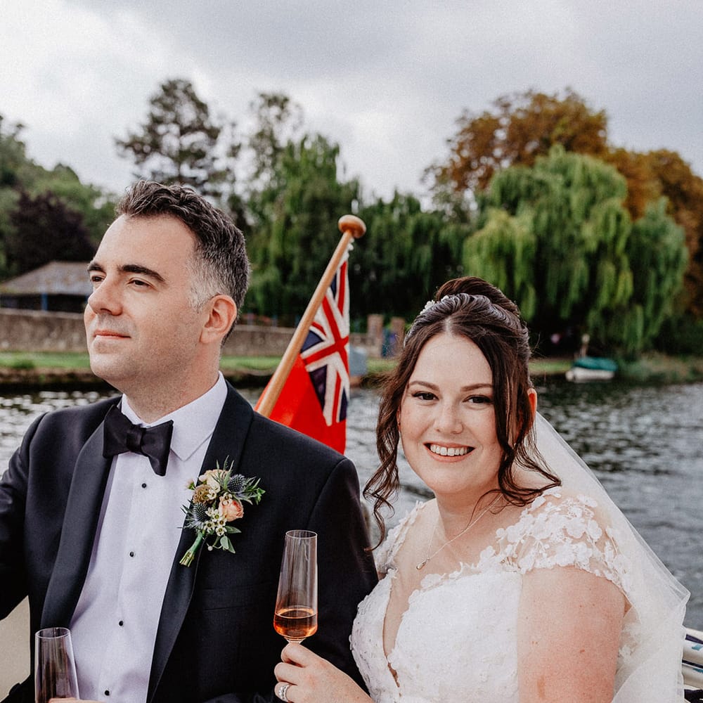 The bride and groom enjoy their boat ride around Henley on Thames for their traditional wedding enjoying some wine 