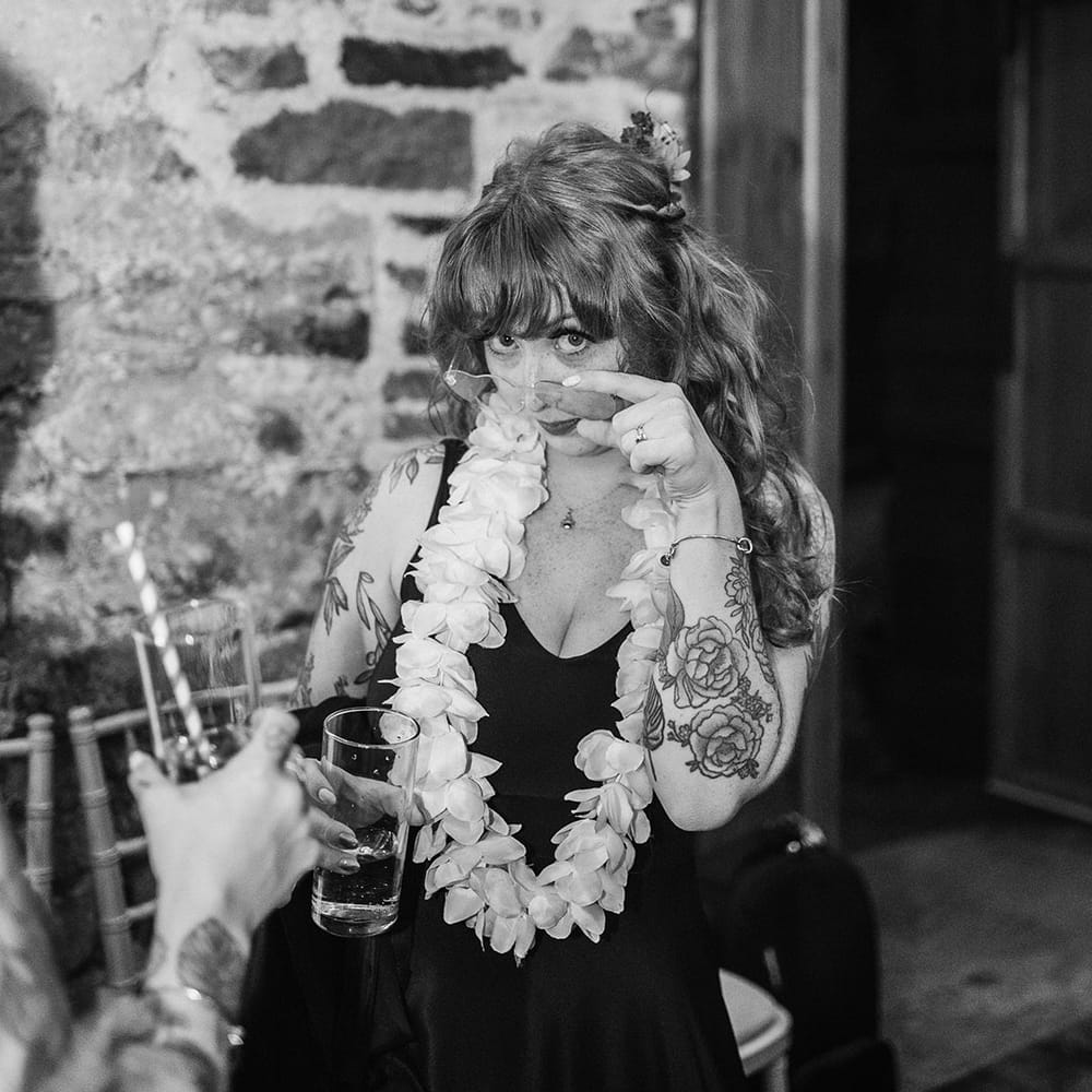 Bride in v neck black wedding dress wearing large colourful wedding lei 