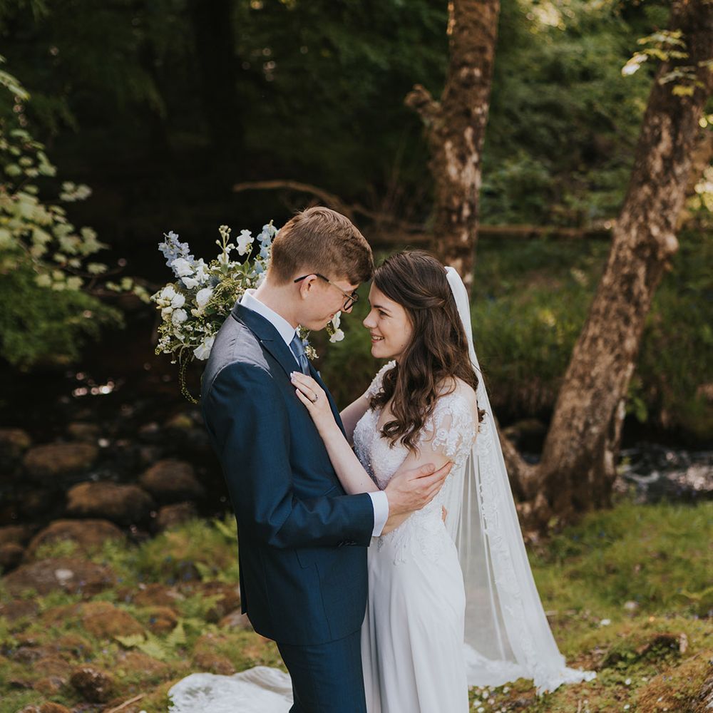 Badgers Holt rustic marquee wedding with the bride and groom posing together in a woodland surrounded by daisies 