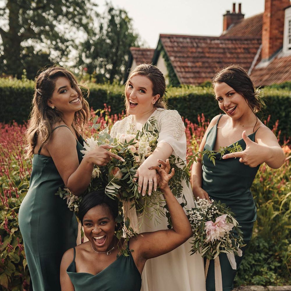 Bride in long sleeve wedding dress with bridesmaids in forest green satin bridesmaid dresses 