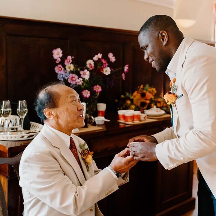 Groom in cream grooms morning suit partaking in Chinese Tea Ceremony wedding tradition at Broadfield Court