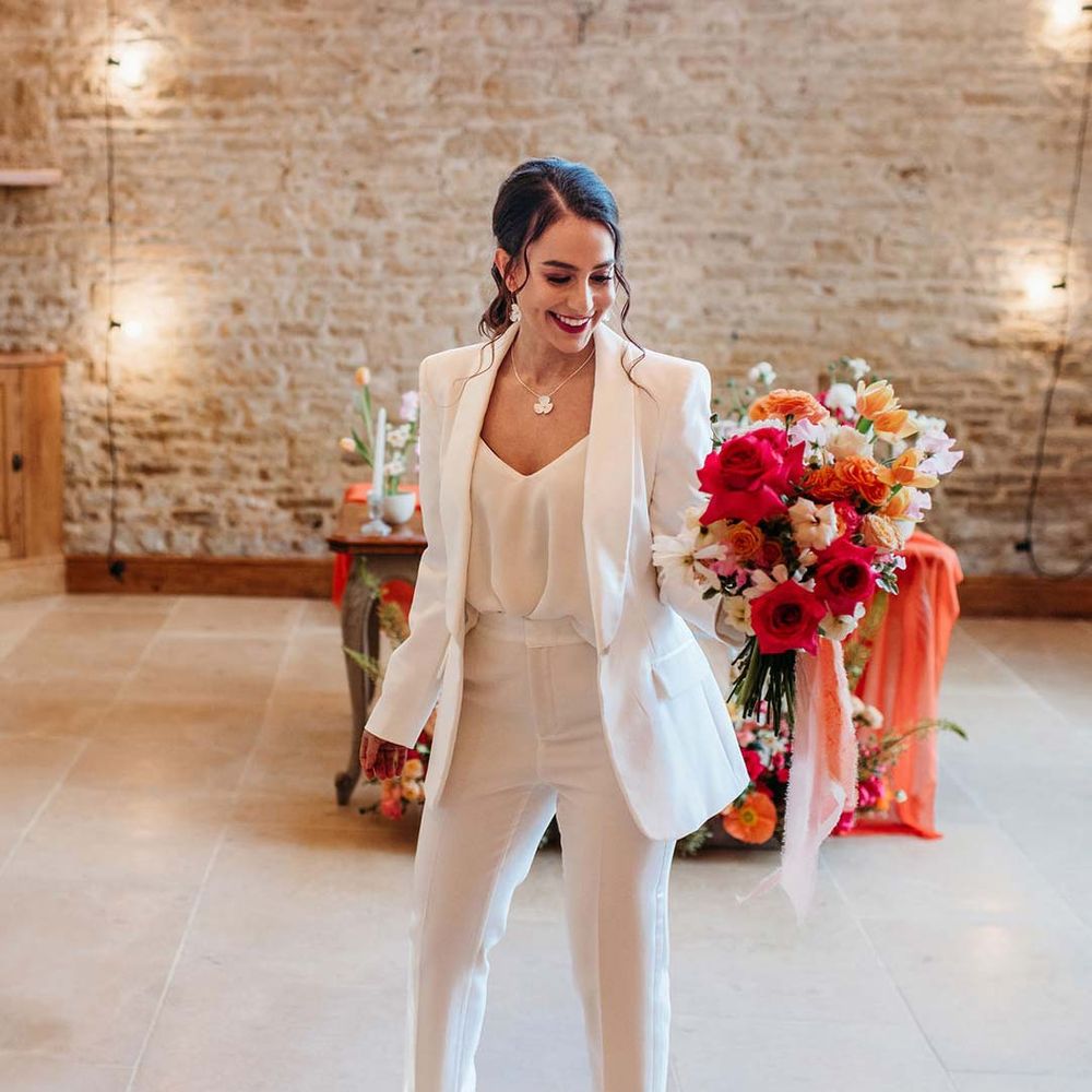 Bride in white bridal suit with closed toe bright green wedding heels holding large seasonal flower bridal bouquet at Merriscourt wedding venue