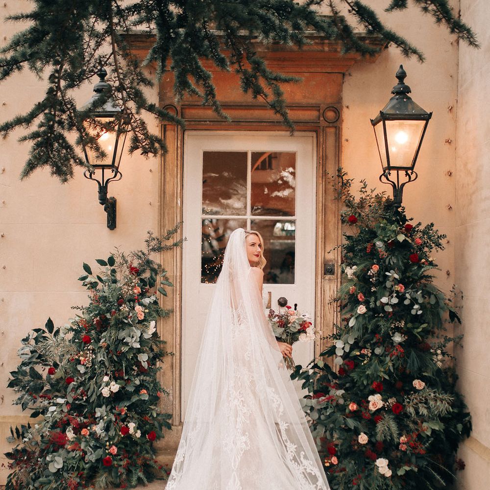 Bride wearing embellished lace wedding with embroidered cathedral length veil walking into Lincolnshire wedding venue 
