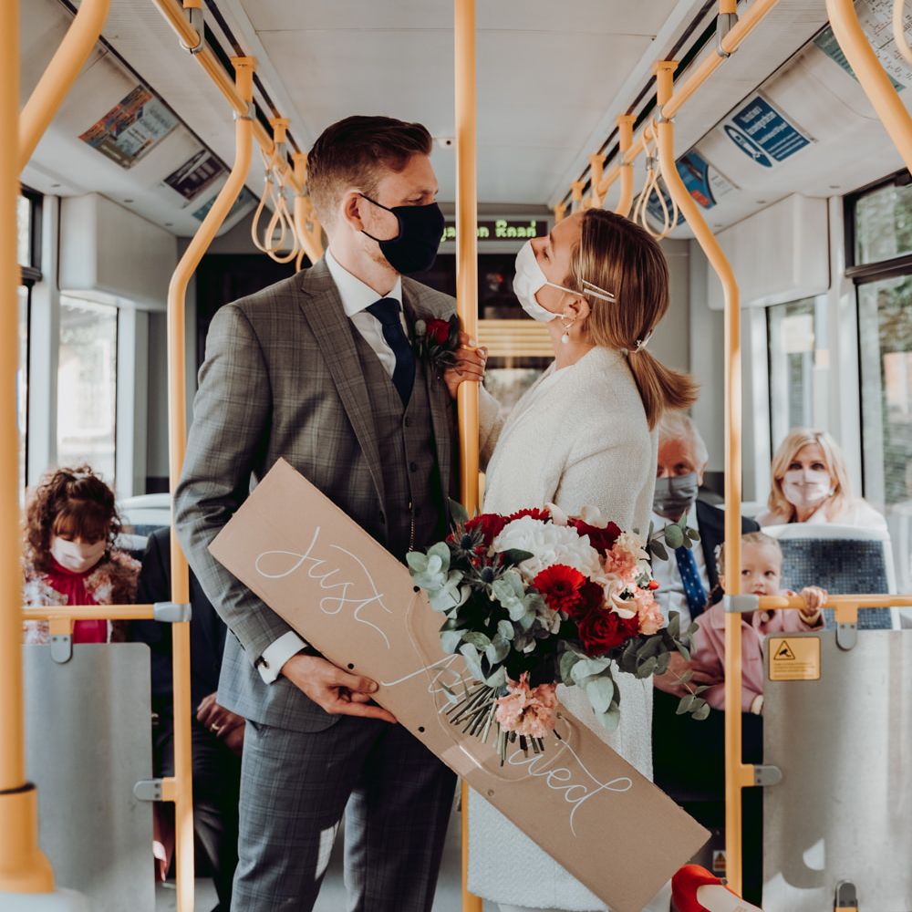 Bride and groom wearing PPE travelling on a tram 