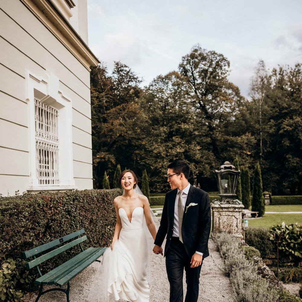 Portrait of the bride and groom walking through the wedding venue grounds by Candida & Max Jan Photography
