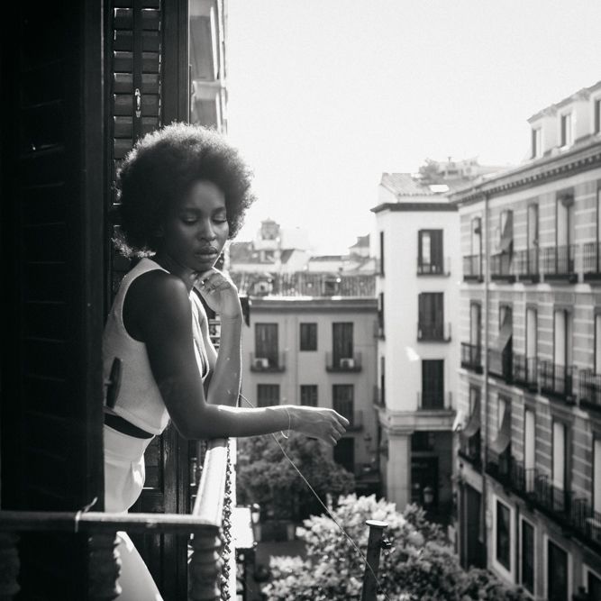 Black & white image of bride stood on balcony 