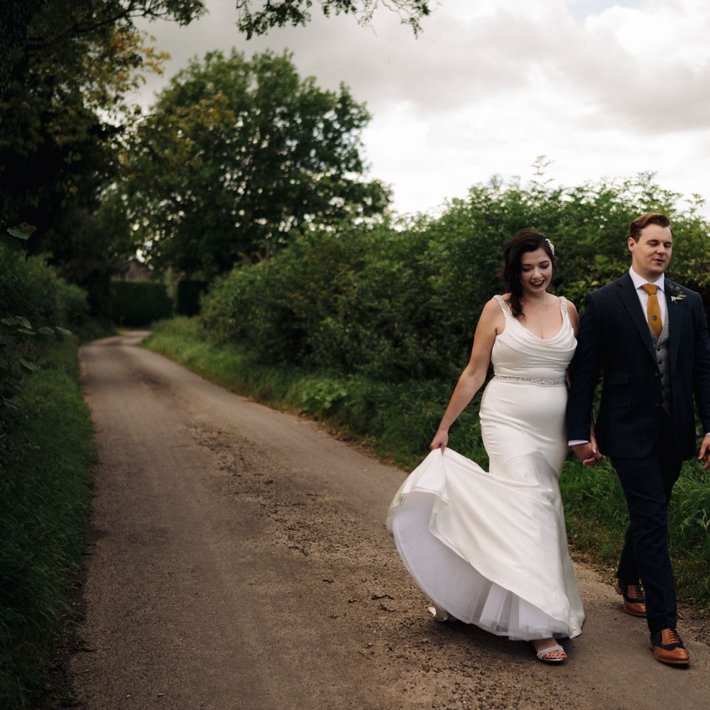 Bride & groom walk through the countryside hand in hand