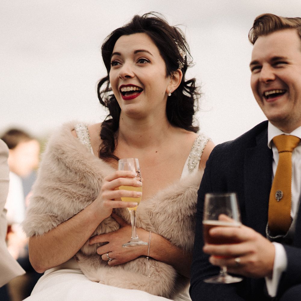 Bride & groom sat together with bride in fur stole 