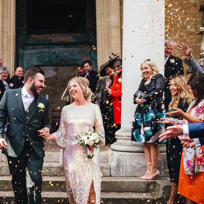 Bride & groom leave wedding ceremony with confetti being thrown around them