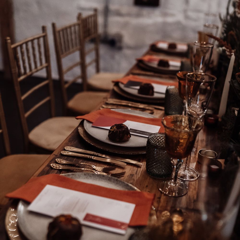 Wedding table decor with orange napkins, coloured glassware and foliage table runner 