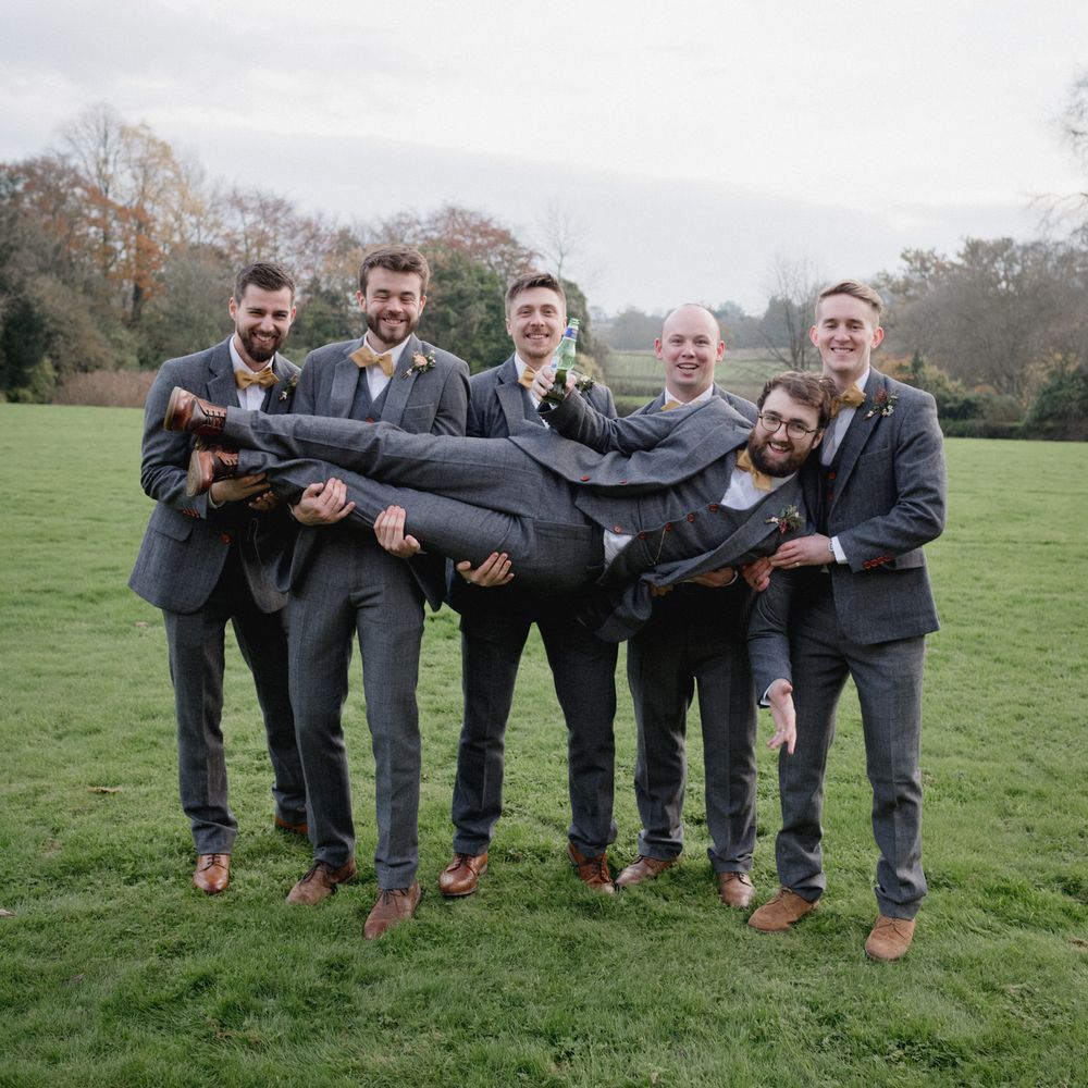 Groomsmen holding groom wearing grey check suits