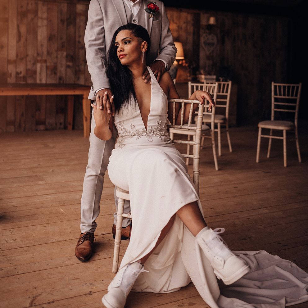 Bride sits down as groom stands behind her and places his hands on her shoulders
